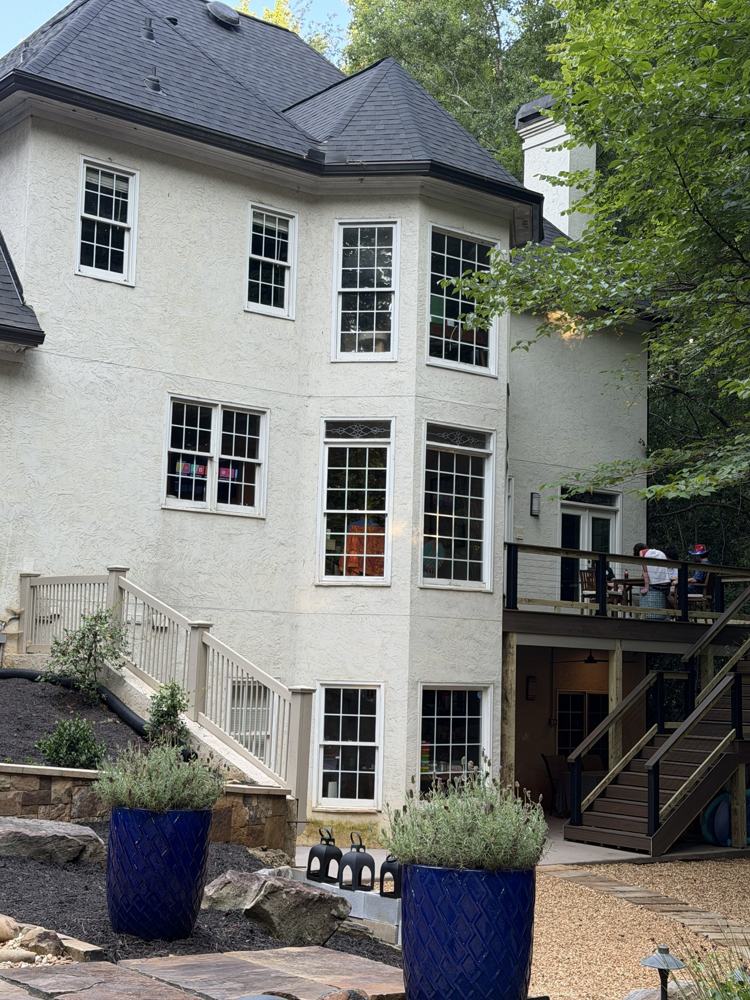 Back of a three-story stucco home with many windows