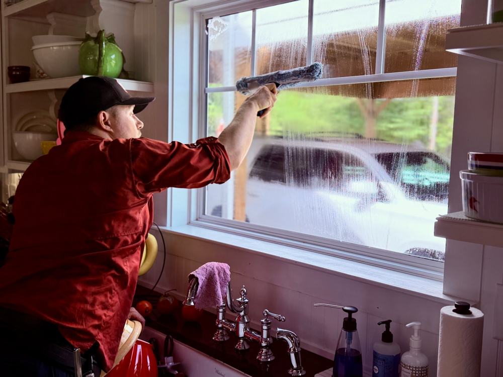 Ryan cleaning a kitchen window in a customer's home