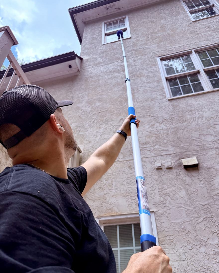 Ryan Olson, owner of TruPro, cleaning third-story windows on a stucco home with an extension pole